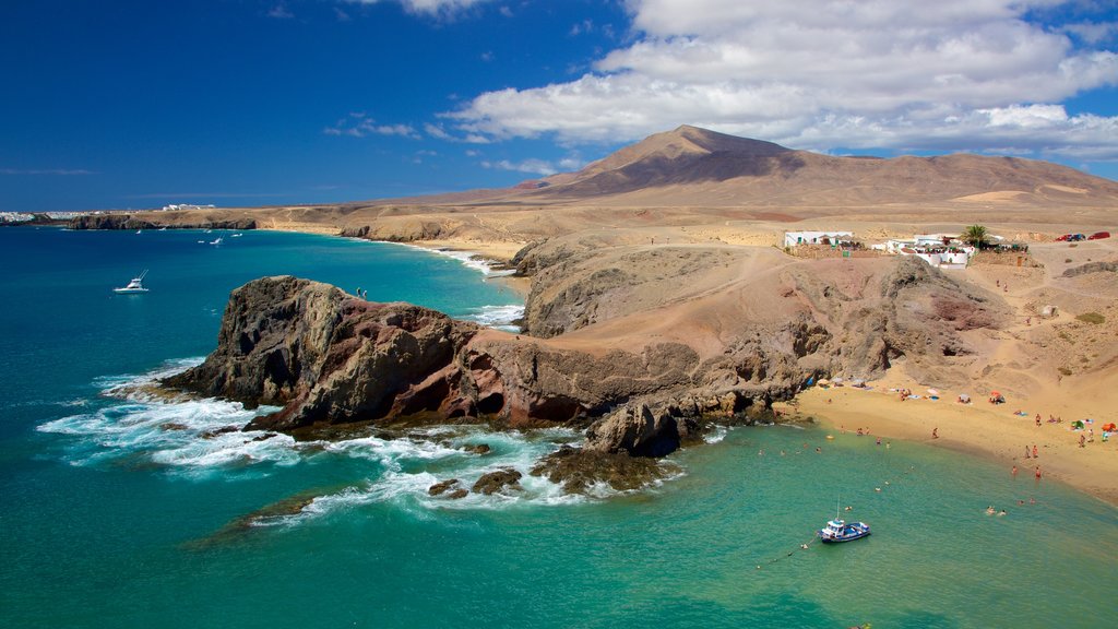 Playa de Papagayo mostrando costa escarpada, una playa y botes