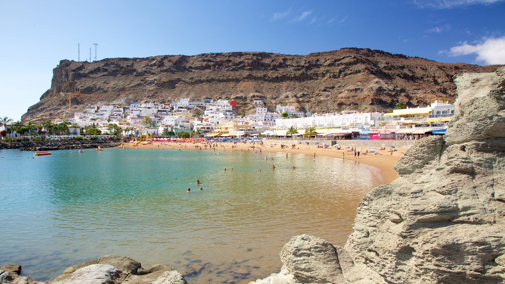 Playa de Mogan showing rocky coastline, a sandy beach and a coastal town