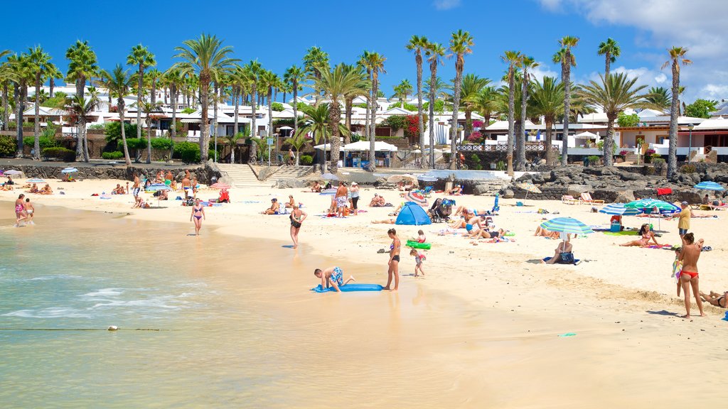 Playa Blanca showing general coastal views and a sandy beach as well as a large group of people