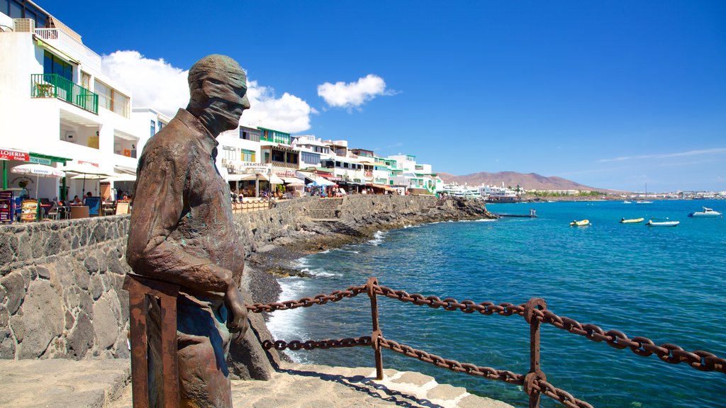 Playa Blanca mostrando litoral rochoso, uma cidade litorânea e uma estátua ou escultura