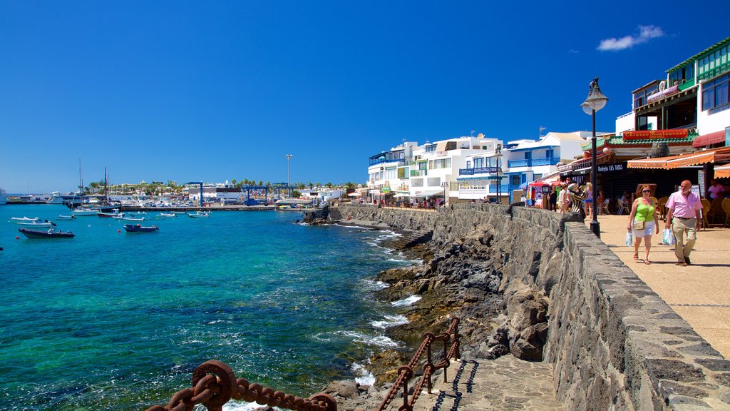 Playa Blanca que incluye paseos en lancha, una ciudad costera y costa rocosa