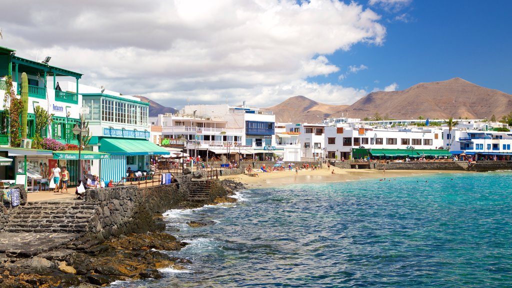 Playa Blanca mostrando litoral rochoso, uma praia de areia e uma cidade litorânea