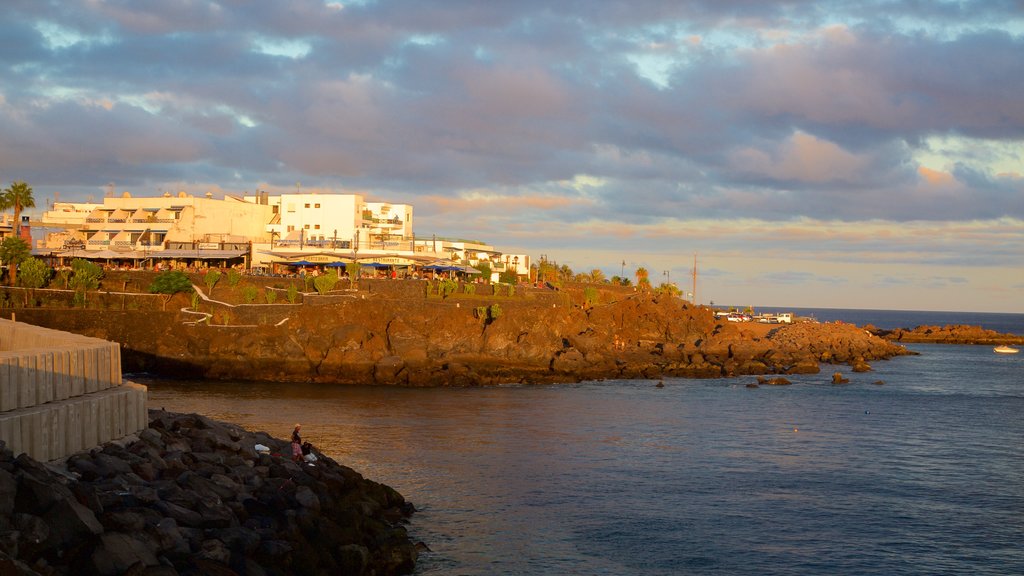 Puerto del Carmen showing rocky coastline, a coastal town and a sunset