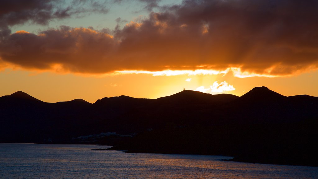 Puerto del Carmen mostrando paisagens litorâneas, montanhas e um pôr do sol