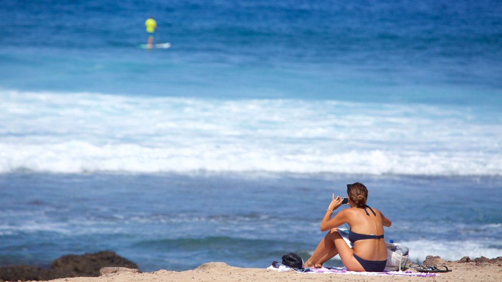 Playa de las Américas que incluye una playa de arena y vistas generales de la costa y también una mujer