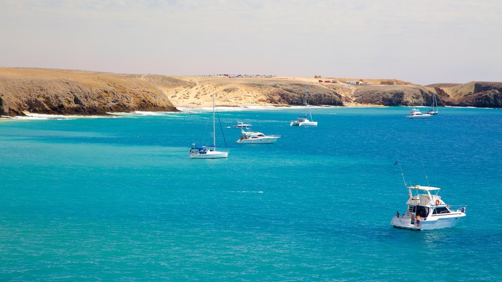 Playa de Papagayo ofreciendo costa rocosa, vista general a la costa y botes