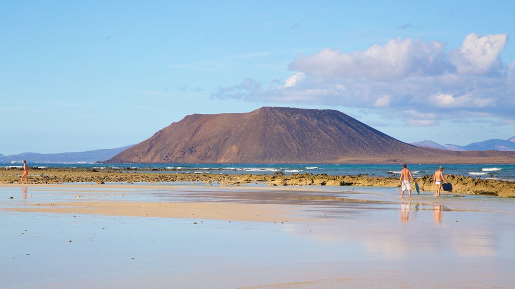 Playa de Corralejo ofreciendo una playa de arena, vistas generales de la costa y montañas