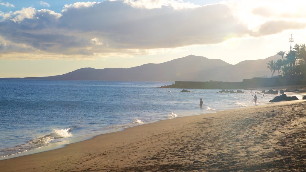 Praia Puerto del Carmen que inclui um pôr do sol, uma praia e paisagens litorâneas