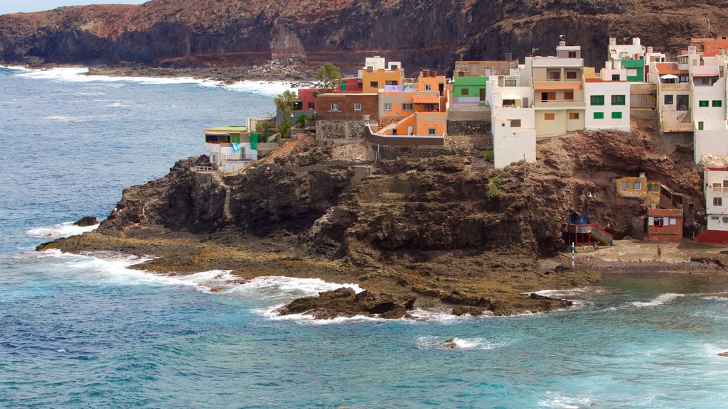 Gran Canaria mostrando costa rocosa, una ciudad costera y una playa de piedras