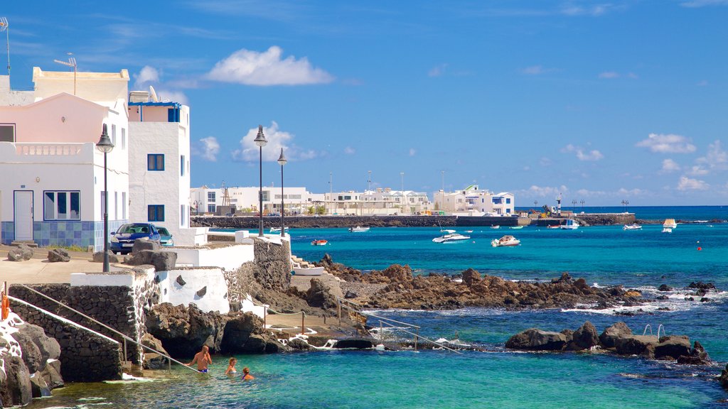 Lanzarote ofreciendo costa rocosa, una ciudad costera y vista general a la costa