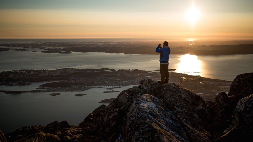 Nuuk which includes a sunset and a lake or waterhole as well as an individual male