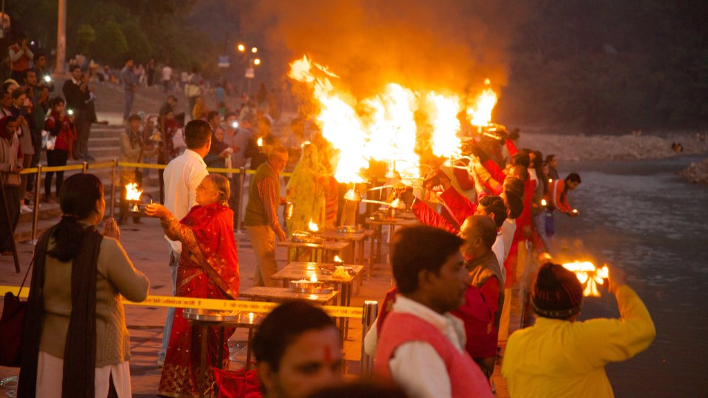 Triveni Ghat , Rishikesh, India que incluye un río o arroyo y aspectos religiosos y también un gran grupo de personas