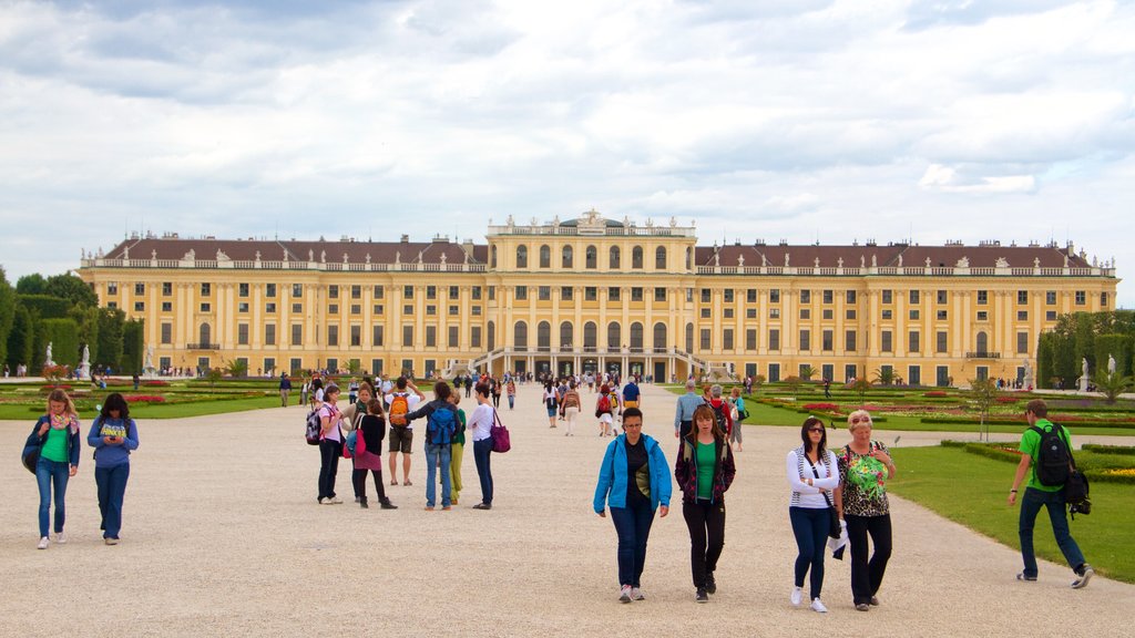 Schonbrunn mostrando arquitetura de patrimônio e um pequeno castelo ou palácio assim como um grande grupo de pessoas