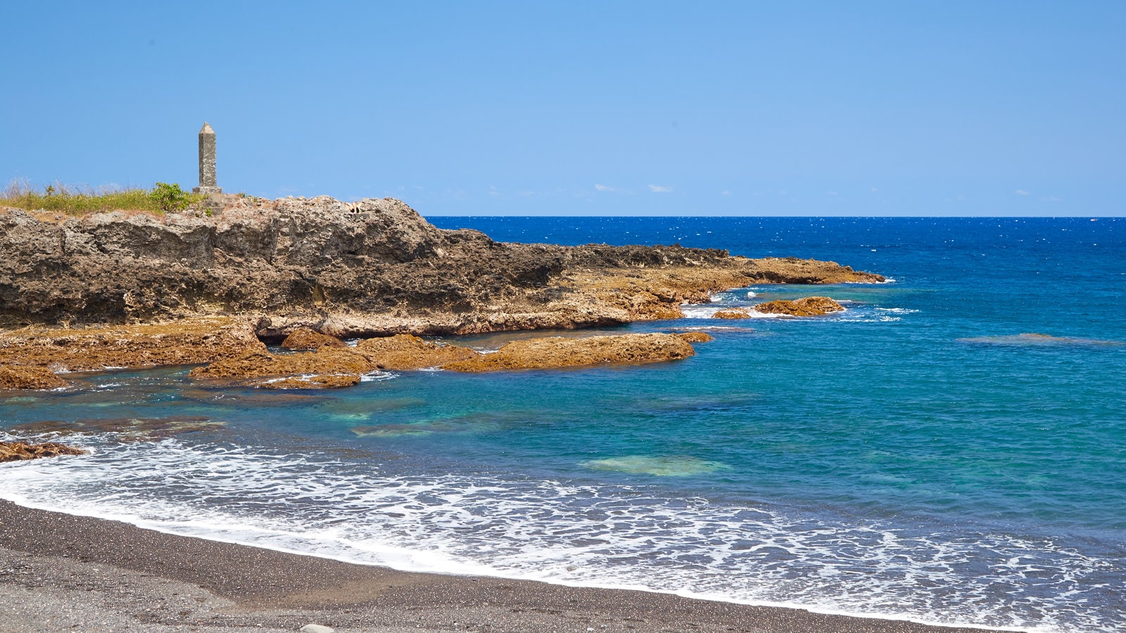 Isla Tanna que incluye litoral rocoso, una playa de guijarros y vistas de una costa