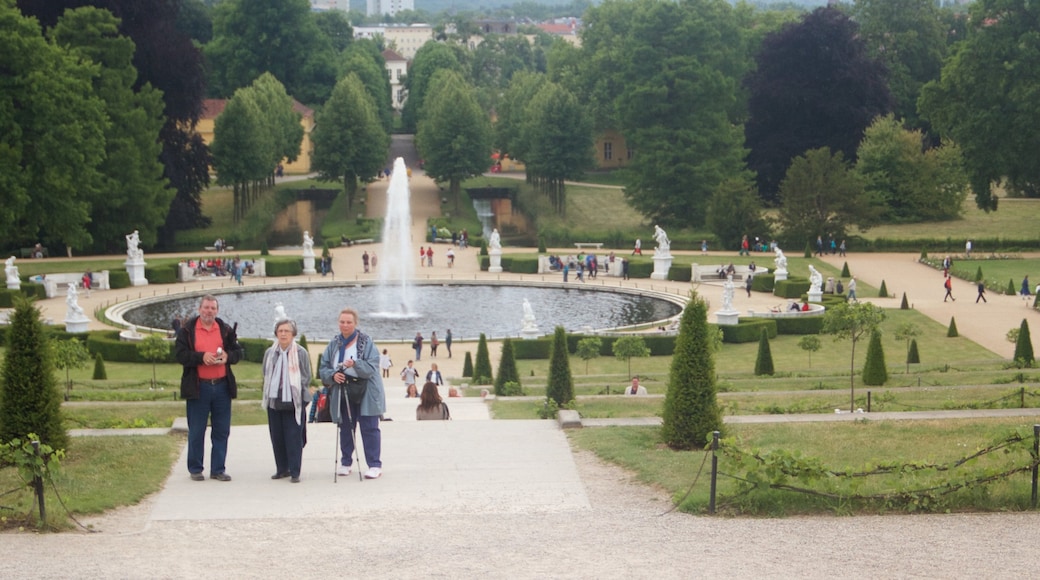 Castello di Sanssouci che include fontana e castello cosi come un piccolo gruppo di persone