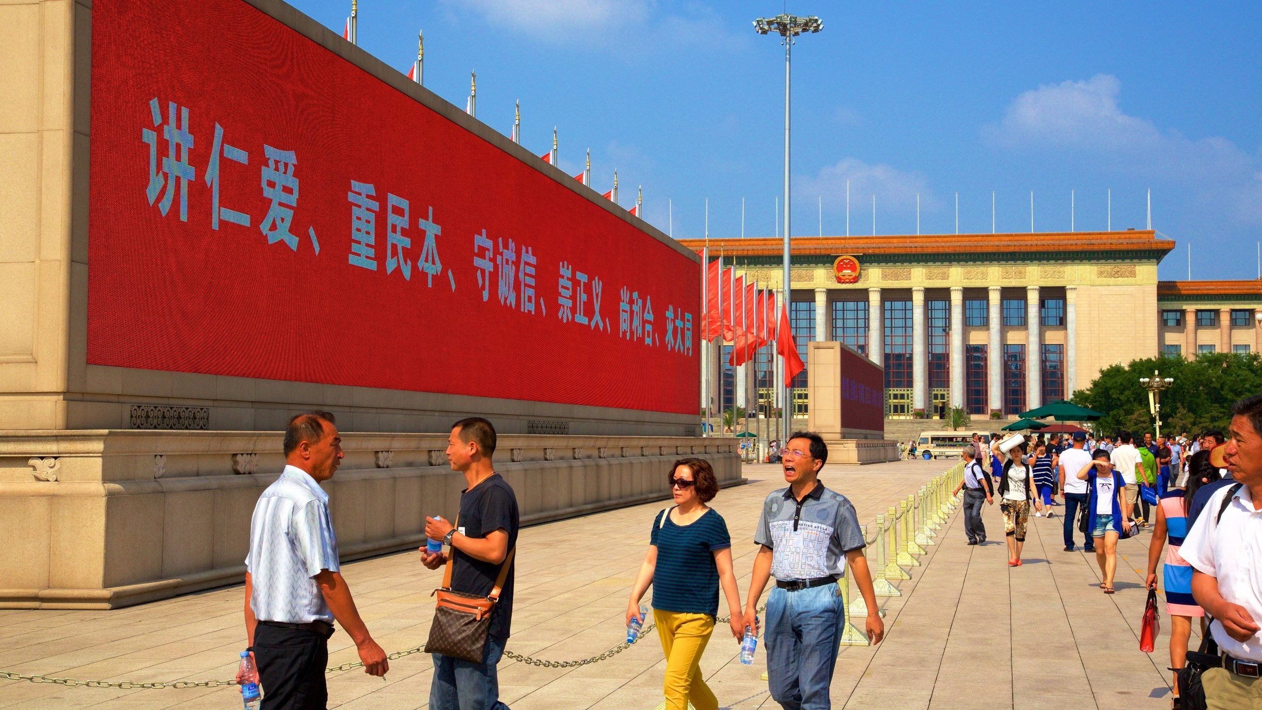 Tiananmen Square som inkluderer skilt i tillegg til en liten gruppe med mennesker