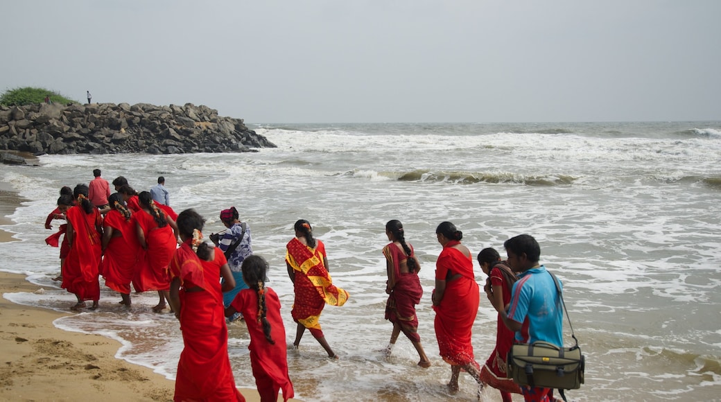 Praia de Mamallapuram caracterizando uma praia de areia assim como um pequeno grupo de pessoas