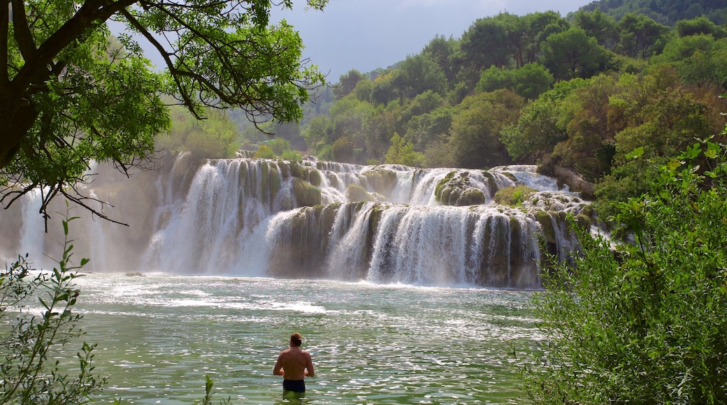 Krka nasjonalpark som viser innsjø og fossestryk i tillegg til en mann