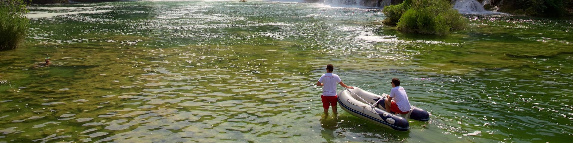 Nationalpark Krka welches beinhaltet Stromschnellen und See oder Wasserstelle sowie kleine Menschengruppe