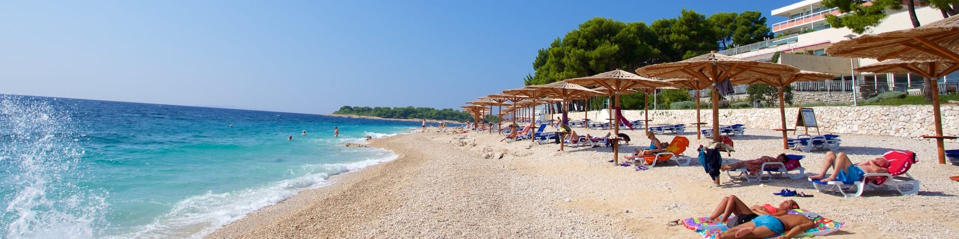 Primosten Beach showing a pebble beach as well as a small group of people