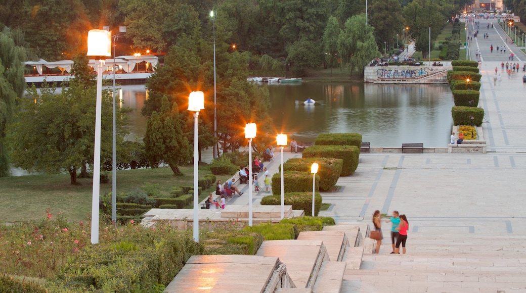 Parque Carol que incluye un jardín y un río o arroyo y también un pequeño grupo de personas