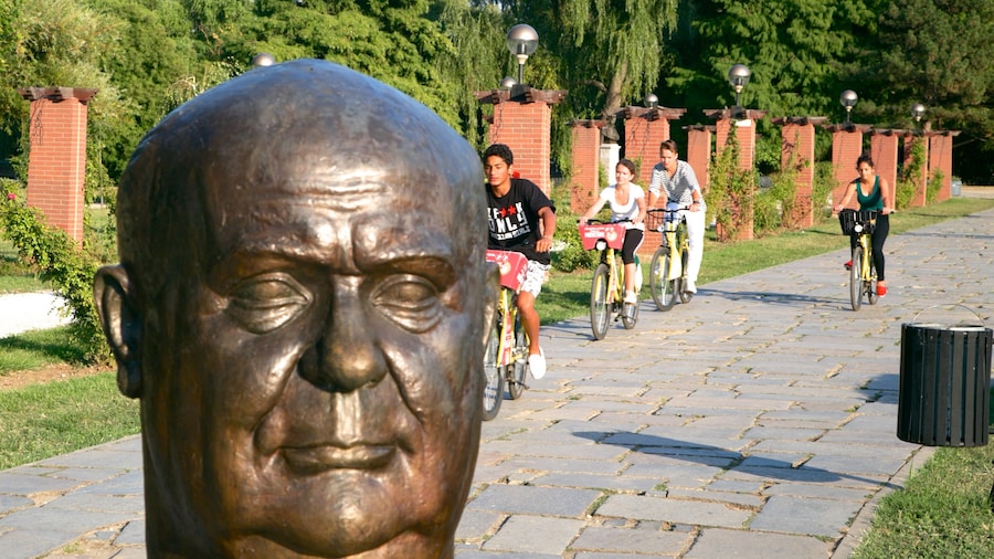 Herastrau Park featuring cycling and a statue or sculpture as well as a small group of people