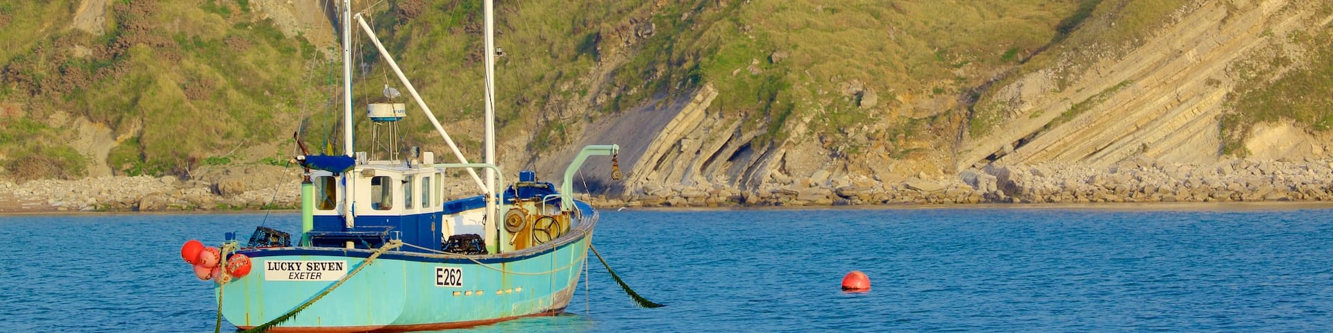 Lulworth Cove Beach featuring rugged coastline and boating