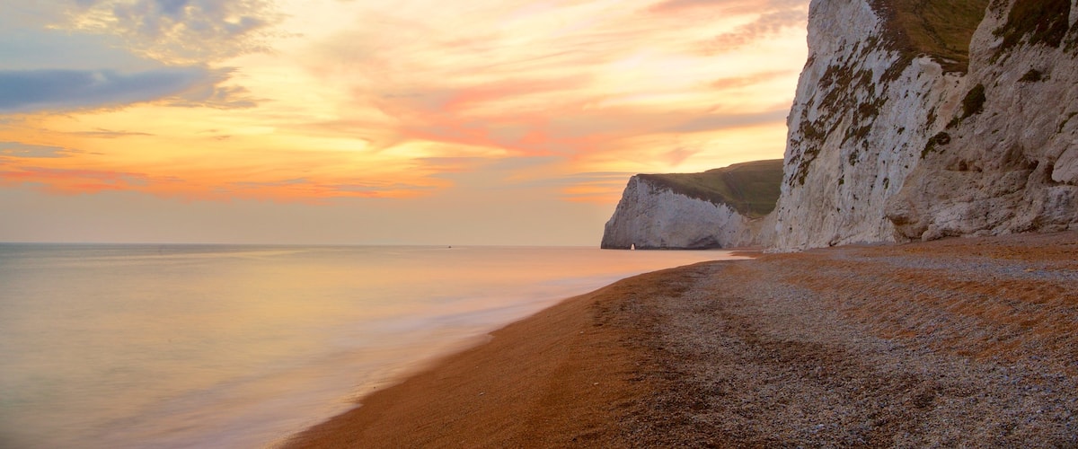 Durdle Door which includes rugged coastline, a pebble beach and a sunset