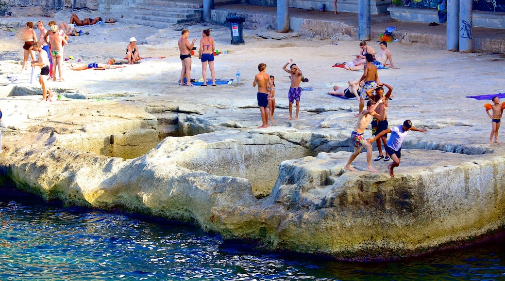 Sliema showing rocky coastline and swimming as well as a large group of people