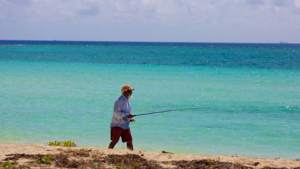 Playa Xanadu ofreciendo pesca y una playa y también un hombre