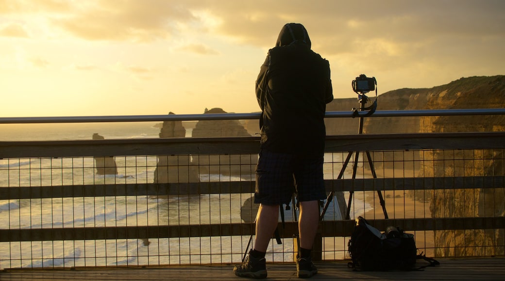 Twelve Apostles welches beinhaltet Sonnenuntergang und Ansichten sowie einzelner Mann