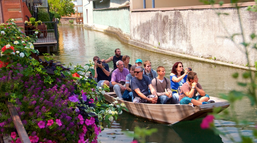 Colmar que incluye flores y botes y también un pequeño grupo de personas