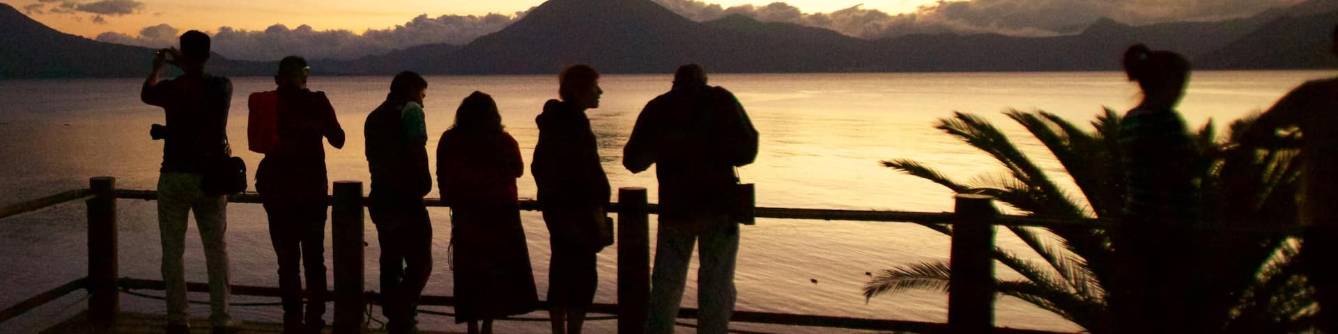 San Pedro Volcano featuring a sunset and general coastal views as well as a small group of people