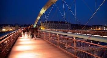 Father Bernatka Footbridge which includes night scenes and a bridge as well as a small group of people