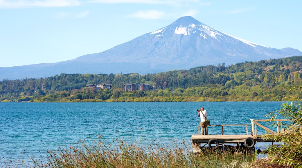 Lago Villarrica mostrando montañas y un lago o espejo de agua y también un hombre