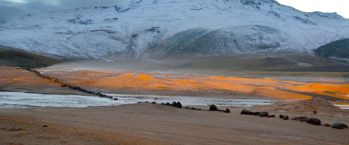 Geysers d\'El Tatio mettant en vedette coucher de soleil, neige et vues du désert