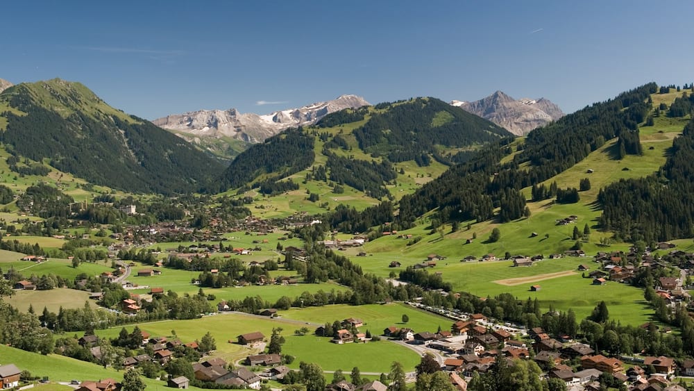 Gstaad which includes mountains, a small town or village and tranquil scenes