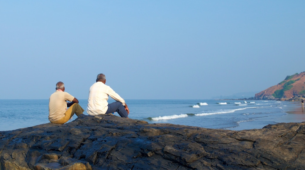 Vagator Beach featuring rocky coastline as well as a small group of people