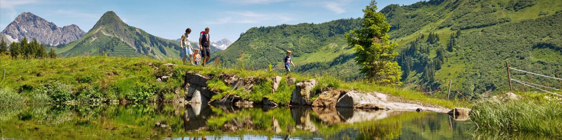 Damuels-Mellau-Fashina Ski Resort featuring mountains and a pond as well as a family