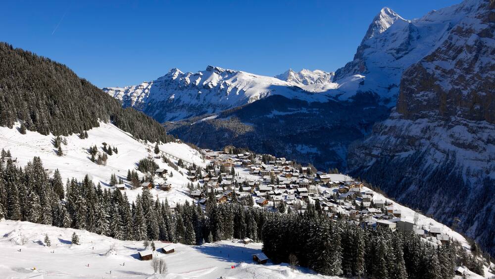 Muerren som omfatter bjerge, sne og en lille by eller en landsby