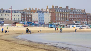 Weymouth che include architettura d\'epoca e spiaggia sabbiosa cosi come un piccolo gruppo di persone