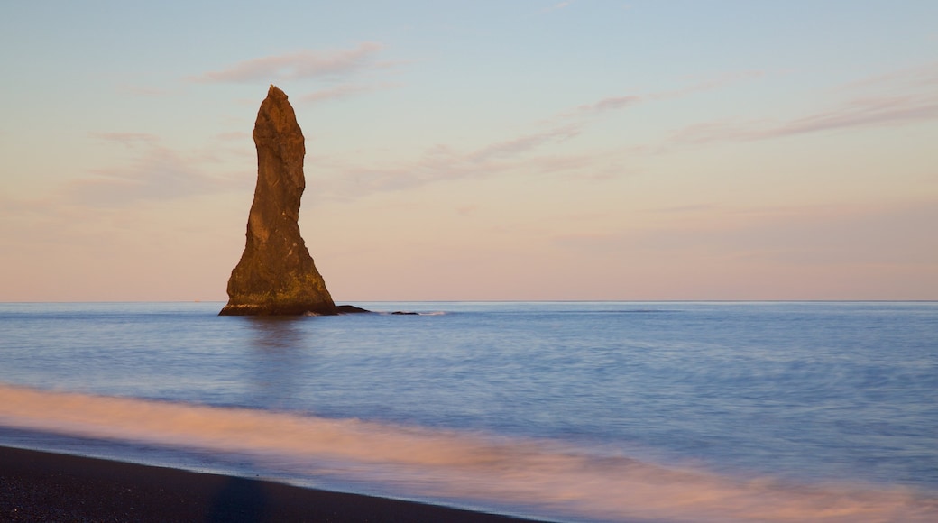 Reynisdrangar ofreciendo vistas generales de la costa, una puesta de sol y una playa de arena