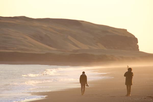 Black Beach showing a sunset and mist or fog as well as a small group of people