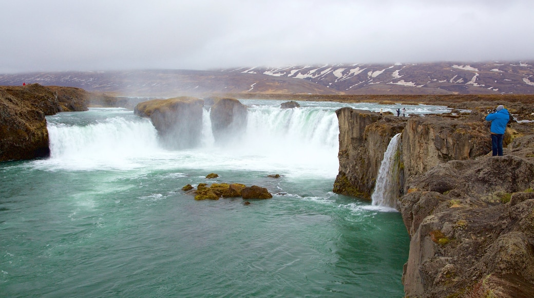 Godafoss mettant en vedette chute d\'eau et brume ou brouillard aussi bien que homme