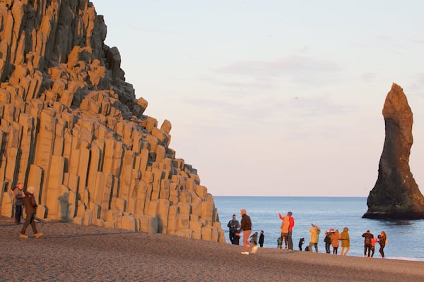 Reynisdrangar which includes general coastal views and a sunset as well as a large group of people