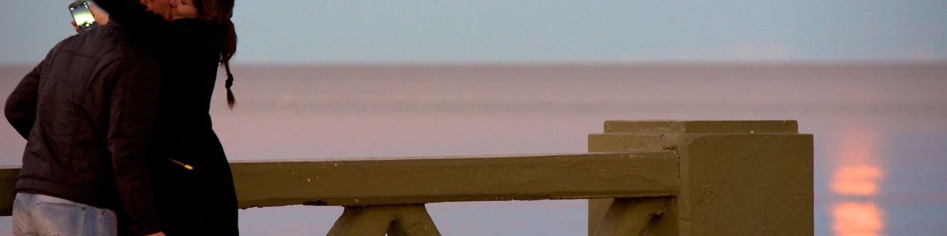 Puerto Madryn Beach showing a sunset as well as a couple