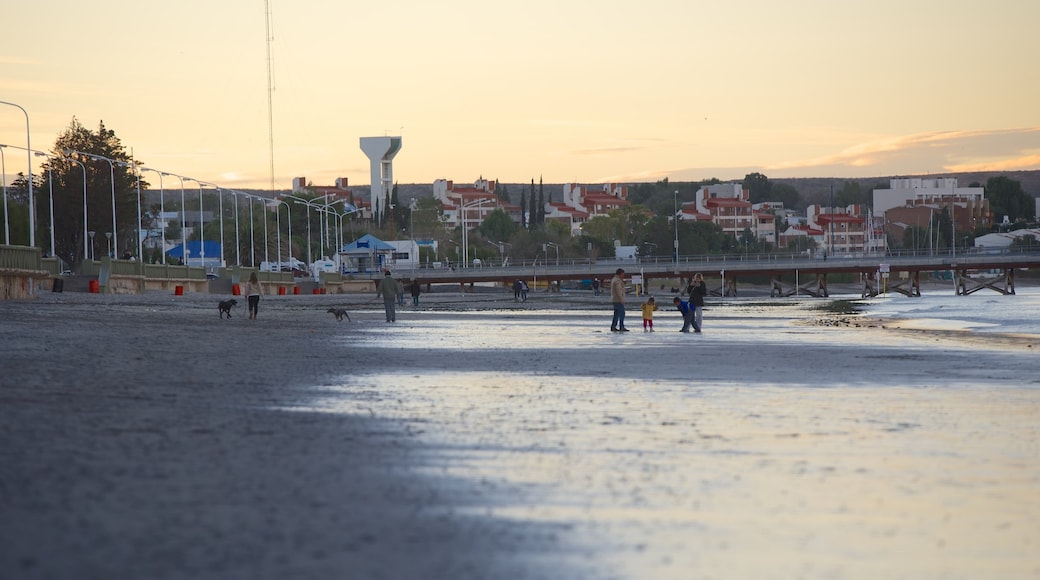 Playa de Puerto Madryn que incluye un atardecer y una playa de arena