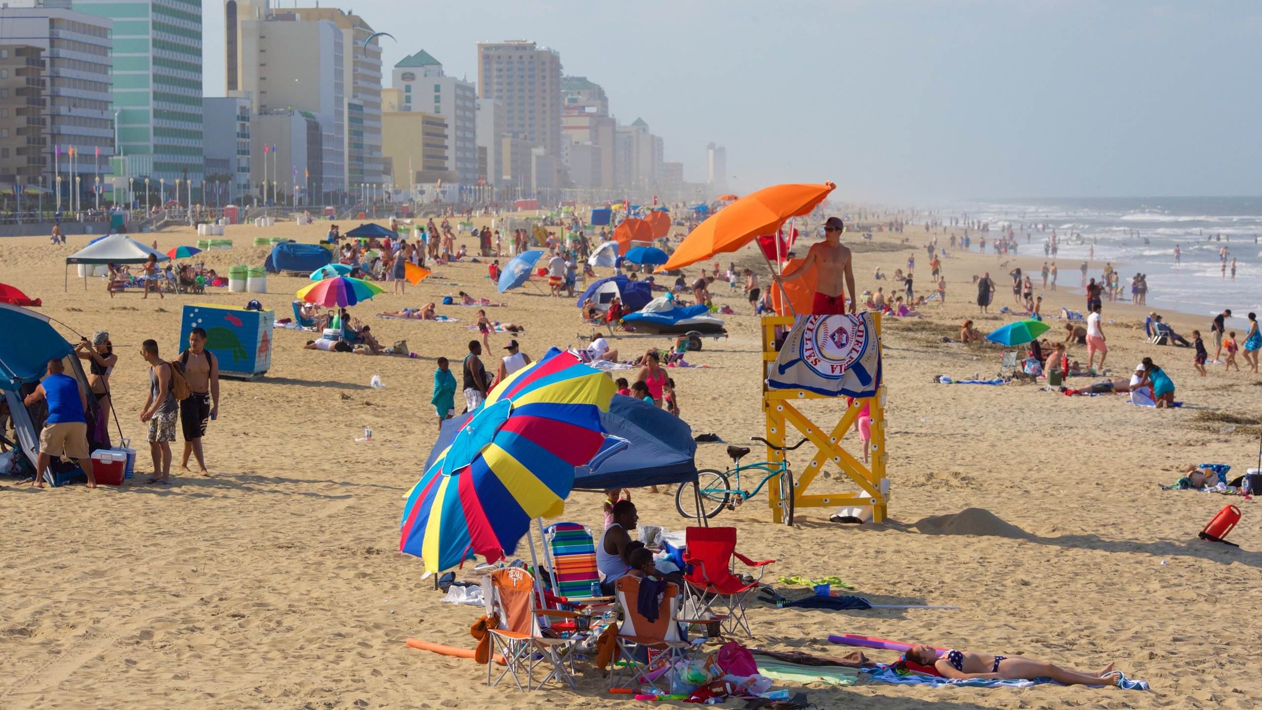 Virginia Beach featuring a sandy beach and a coastal town as well as a large group of people