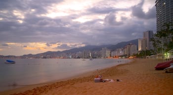 Praia de Icacos que inclui um pôr do sol, uma praia e uma cidade litorânea