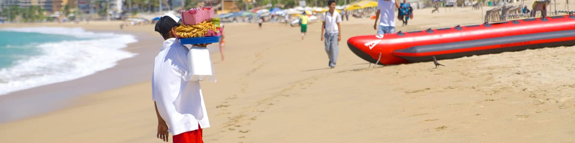 Condesa Beach showing a sandy beach and a coastal town as well as an individual male
